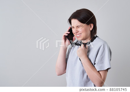 Woman talking on chained mobile phone over grey background, addiction concept Woman talking on chained mobile phone over grey background, addiction concept 88105745