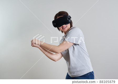 Happy young woman playing on VR glasses indoor, Virtual reality concept with young girl having fun with headset goggles, with copy space Happy young woman playing on VR glasses indoor, Virtual reality concept with young girl having fun with headset goggles, with copy space 88105879