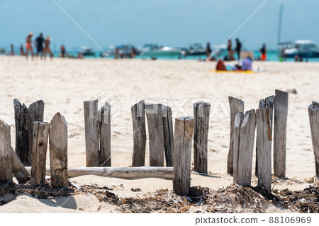 Old wooden beams from former pier on a beautiful caribbean beach on Isla Muheres, Mexico 88106969