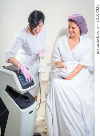 woman in a beauty salon discuss anti-aging treatment with cosmetologist looking through magazine woman in a beauty salon discuss anti-aging treatment with cosmetologist looking through magazine 88107026