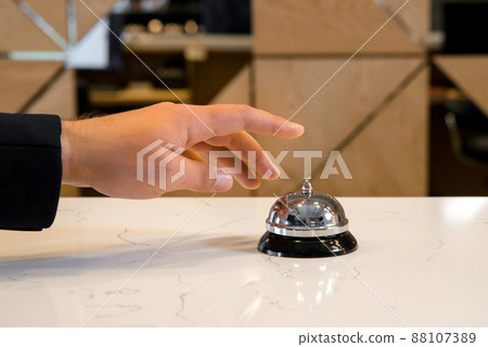 Hand of a man is going to use a vintage hotel bell Hand of a man is going to use a vintage hotel bell 88107389