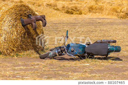 A motorycle near the haystack and boots in the pile of straw. crash humor concept decoration 88107465