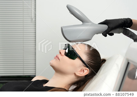 Young woman receiving laser treatment in cosmetology clinic Young woman receiving laser treatment in cosmetology clinic 88107549