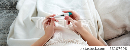 Woman holding a digital thermometer. Concept of fever, flue, virus and quarantine Woman holding a digital thermometer. Concept of fever, flue, virus and quarantine 88107698