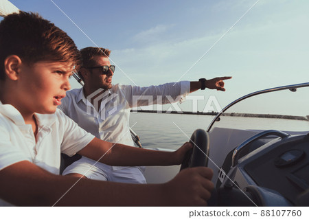 Father and son enjoy their vacation together while riding a luxury boat at sea. Selective focus Father and son enjoy their vacation together while riding a luxury boat at sea. Selective focus 88107760