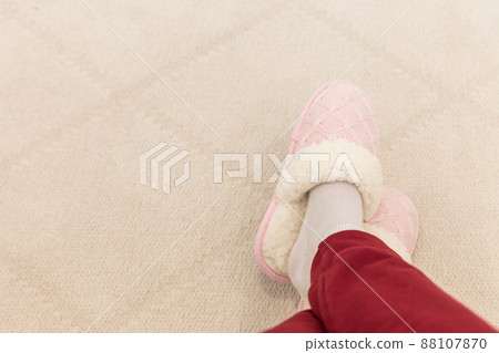 Crossed legs wearing pink knitted slippers Crossed legs wearing pink knitted slippers 88107870