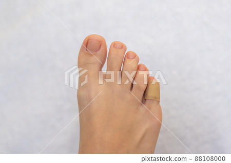 Medical plaster on the female little toe. Wound at toe healed with a band aid for medical care Medical plaster on the female little toe. Wound at toe healed with a band aid for medical care 88108000