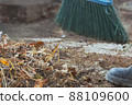 pile of garden debris and broom sweeping the yard 88109600