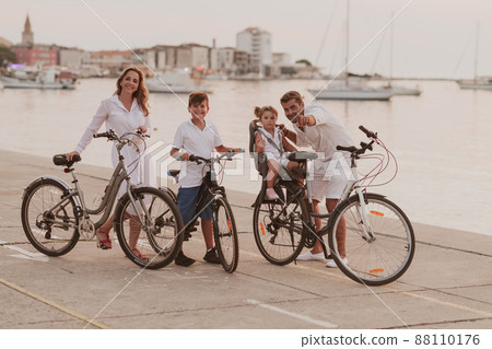 The happy family enjoys a beautiful morning by the sea riding a bike together and spending time together. The concept of a happy family The happy family enjoys a beautiful morning by the sea riding a bike together and spending time together. The concept of a happy family 88110176