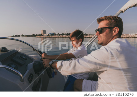 Father and son enjoy their vacation together while riding a luxury boat at sea. Selective focus Father and son enjoy their vacation together while riding a luxury boat at sea. Selective focus 88110276