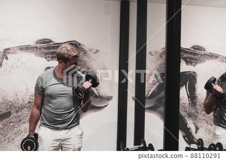 Struggling with age. Confident senior man exercising with dumbbells in health club. Selective focus Struggling with age. Confident senior man exercising with dumbbells in health club. Selective focus 88110291