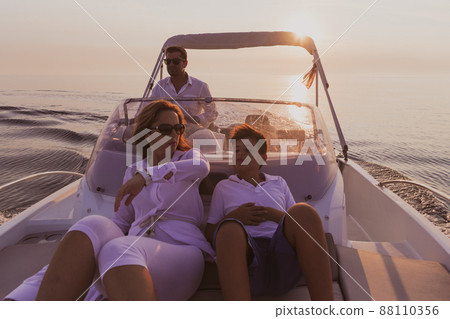 A senior couple in casual outfits with their son enjoy while riding a boat at sea at sunset. The concept of a happy family. Selective focus  88110356