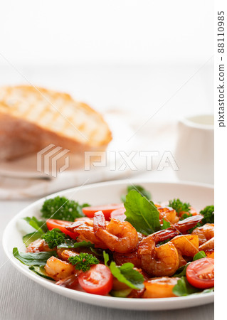 Fresh salad of shrimps, tomatoes, arugula and herbs on a white plate. vertical image 88110985