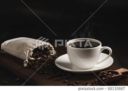 White cup of fresh hot coffee and coffee beans on wooden board on table 88110987