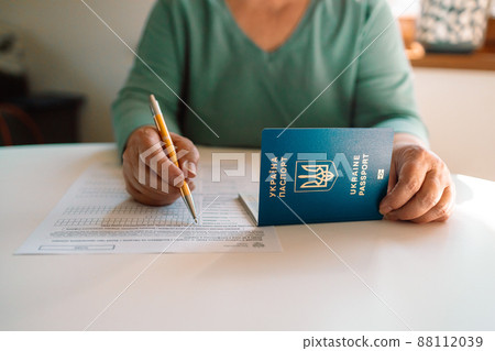 50 60s Caucasian woman hand write with a pen in PESEL document on white table at state service department 50 60s Caucasian woman hand write with a pen in PESEL document on white table at state service department 88112039