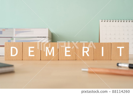 Image of disadvantages | Desk with building blocks with "DEMERIT" written on it 88114260