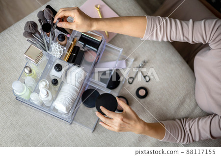 Closeup female hands putting luxury cosmetic into acrylic box with drawer storage organization 88117155