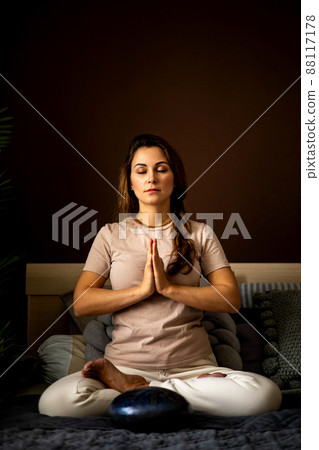 Relaxed yoga woman meditation in lotus position with hands namaste on bed at bedroom 88117178