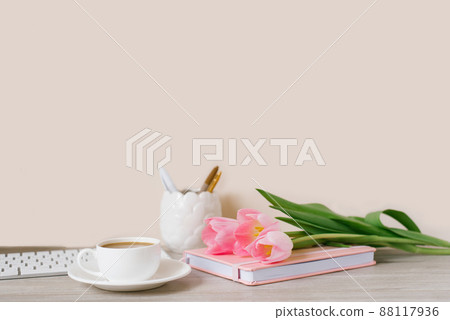 Home office workplace: cup of coffee, notebook, keyboard, tulip flowers, brushes, on wooden background background. Copy space 88117936