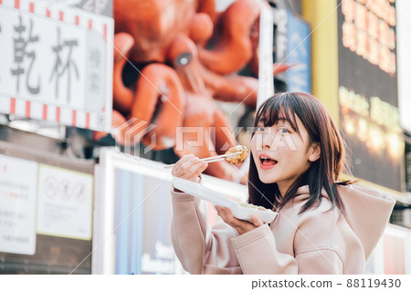 A woman eating takoyaki in Minami, Osaka 88119430