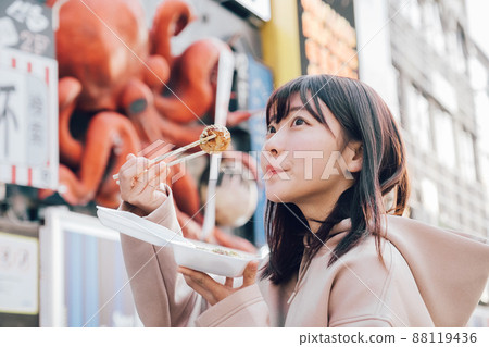A woman eating takoyaki in Minami, Osaka 88119436