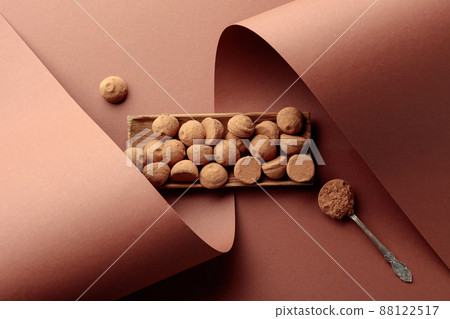 Tasty chocolate truffles and spoon with cocoa powder. 88122517