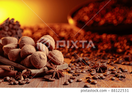 Chocolate truffles with cinnamon, anise, and coffee beans on a wooden table. 88122531