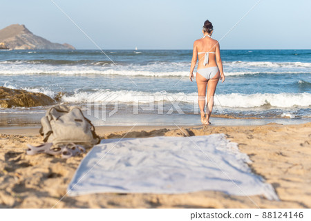 Anonymous woman in swimsuit on sandy seacoast 88124146