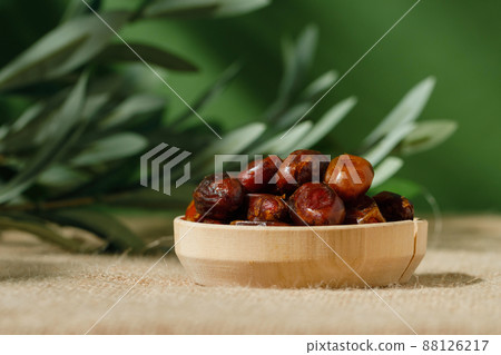 dried dates in a wooden plate on a green background on a sunny day. dried dates in a wooden plate on a green background on a sunny day. 88126217