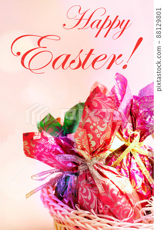 Easter greeting card with decorative eggs wrapped in color patterned paper close up on pastel pink backdrop with inscription Happy Easter and color bokeh lights. Vertical orientation. 88129801
