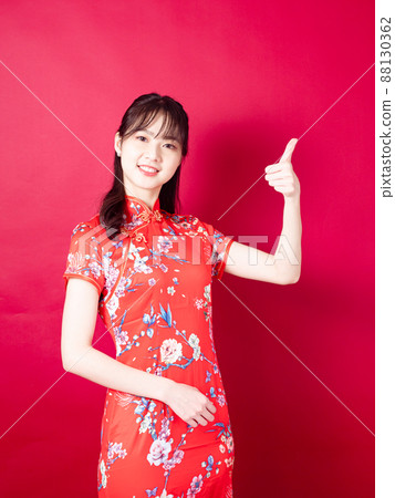 Asian woman wearing traditional cheongsam qipao dress with gesture of introduce isolated on red background. 88130362