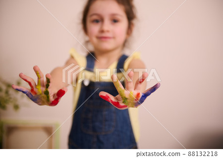 The main focus is on children's hands stained with paints during a creativity lesson. Blurred baby girl showing her hands with colorful paints to the camera The main focus is on children's hands stained with paints during a creativity lesson. Blurred baby girl showing her hands with colorful paints to the camera 88132218