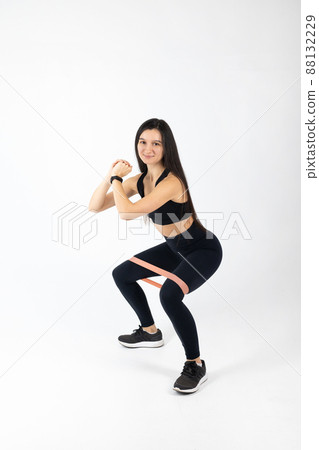 Sportswoman exercising with resistance band on white background. Attractive brunette woman in fashionable sportswear exercising. Healthy lifestyle, sport concept, Full length view 88132229