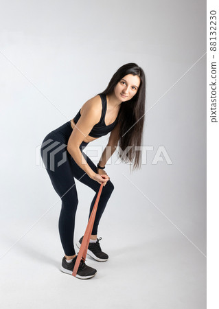 Sportswoman exercising with resistance band on white background. Attractive brunette woman in fashionable sportswear exercising. Healthy lifestyle, sport concept, Full length view 88132230