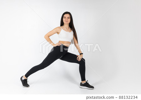 Fitness girl doing stretching workout on white background. Attractive brunette woman in fashionable sportswear exercising. Healthy lifestyle, sport concept, Full length view 88132234