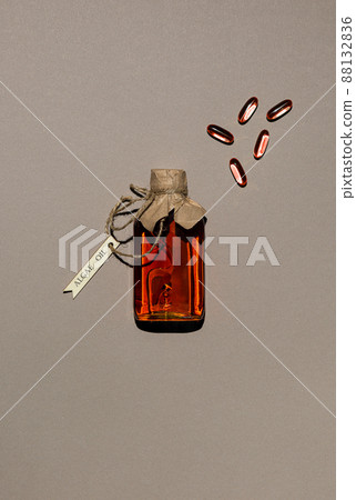 Glass bottle with algae oil and few capsules on brown paper 88132836