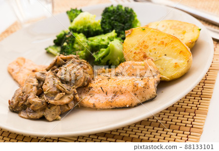 fried river trout fillet with a complex side dish of broccoli, baked potatoes and mushroom sauce 88133101