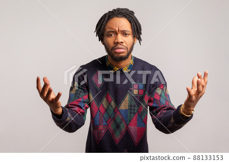 Worried exhausted african man with dreadlock spreading hands asking what, tired irritated of questions, misunderstanding. Indoor studio shot isolated on gray background 88133153