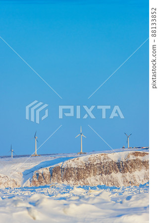 Wind farm in the Arctic on the sea coast. Wind turbines on a high rocky shore against a blue sky. 88133852