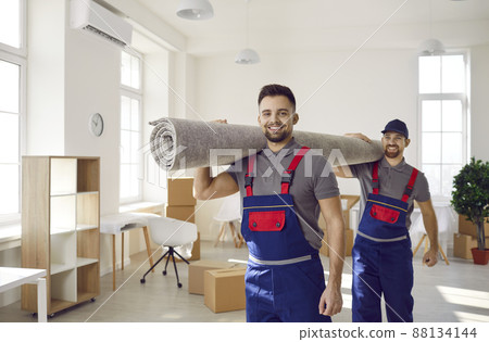 Smiling male movers carrying carpet on shoulders Smiling male movers carrying carpet on shoulders 88134144