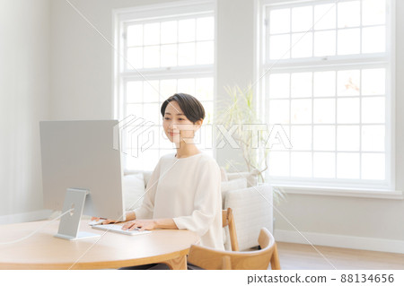 A woman who operates a personal computer at home 88134656