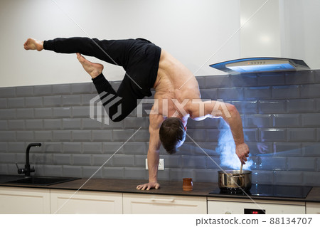 Man exercising handstand and eating fruits in the kitchen. Concept of yoga, healthy diet and lifestyle  88134707