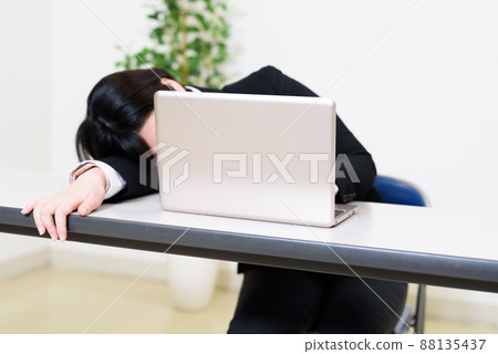 A young woman who skips while looking at a computer from tiredness, a conference room, a break, overtime, pantsuit A young woman who skips while looking at a computer from tiredness, a conference room, a break, overtime, pantsuit 88135437