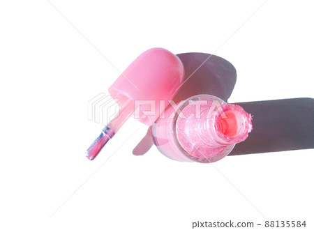 Isolated pink nail bottle on a white background with an open lid with a brush next to it, shade from sunlight, top view 88135584