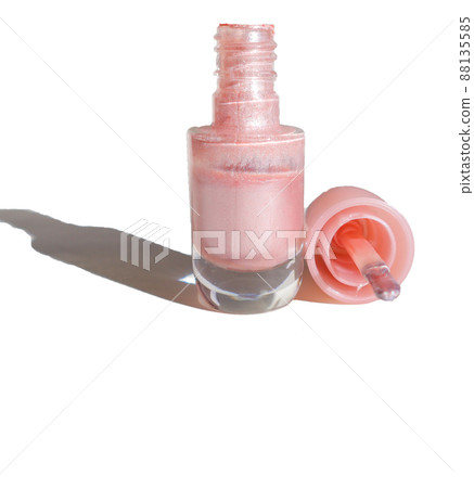 Insulated pink nail bottle on a white background with an open lid with a brush next to it, shade from sunlight 88135585