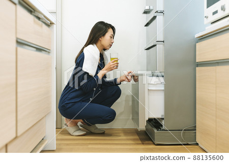 A woman opening the refrigerator in her pajamas 88135600