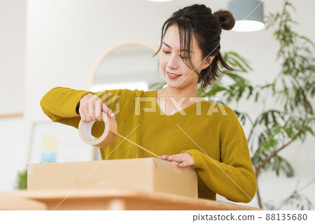 A woman who puts gum tape on cardboard 88135680