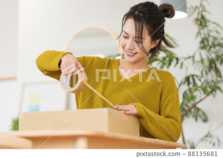 A woman who puts gum tape on cardboard A woman who puts gum tape on cardboard 88135681