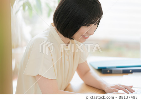 A woman heading to a computer at home 88137485