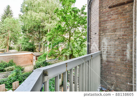 Small balcony with metal railings and brick walls on the sides in a cozy house 88138605
